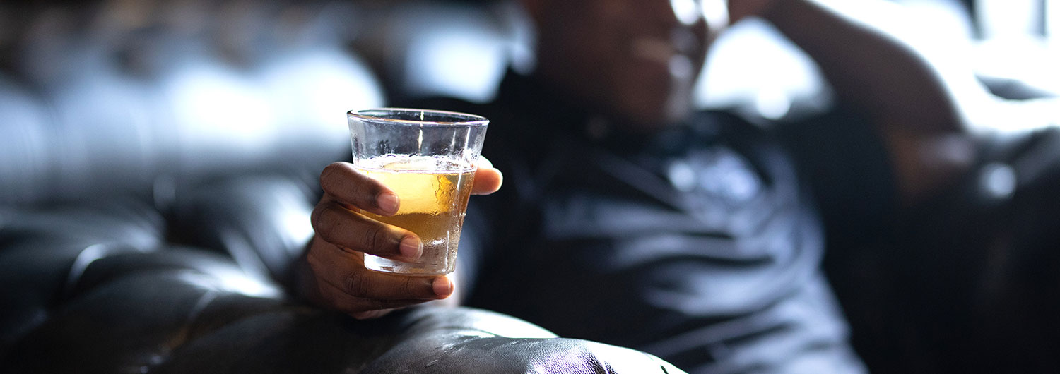 Man sitting holding a glass of whiskey