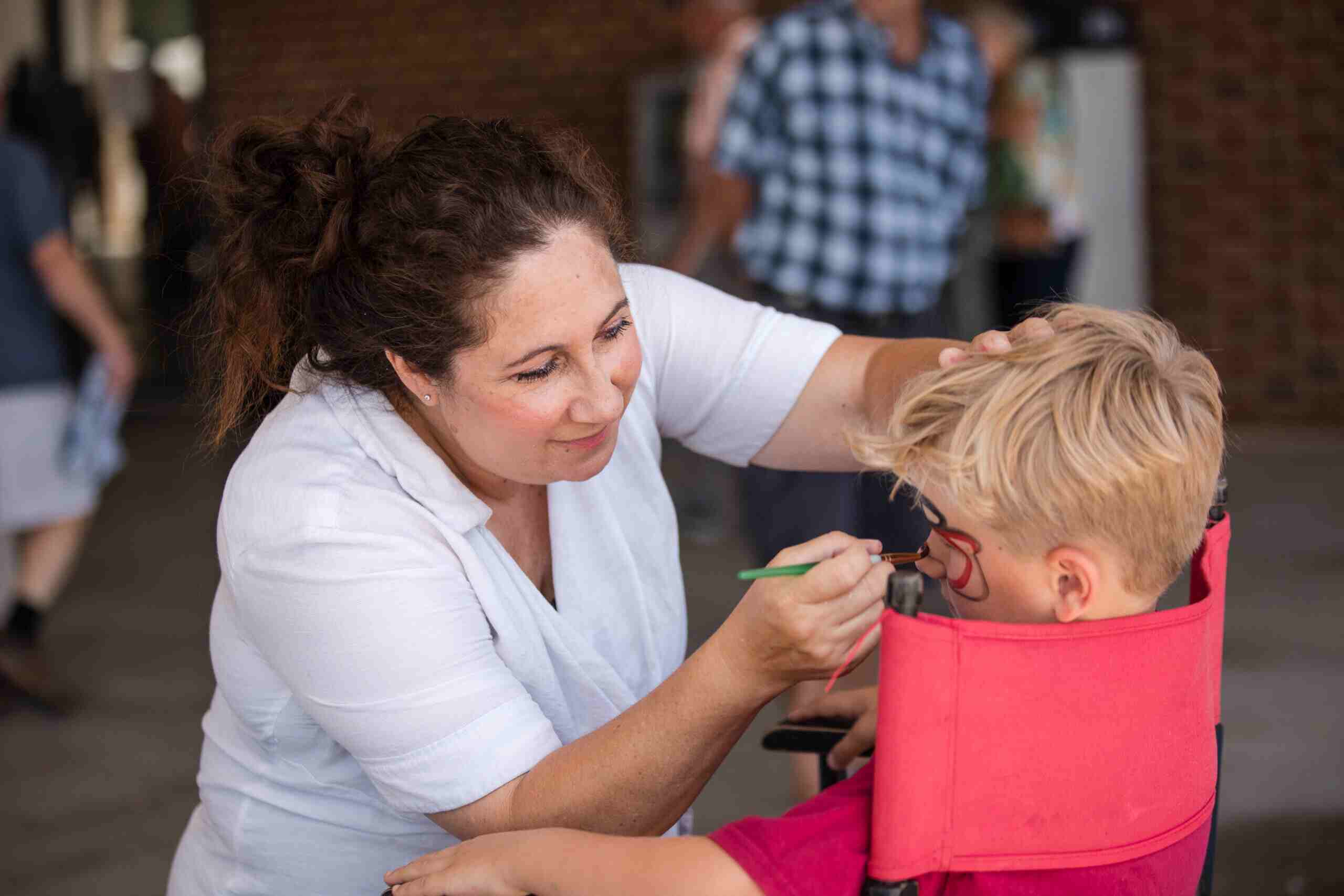 Woman painting kid's face