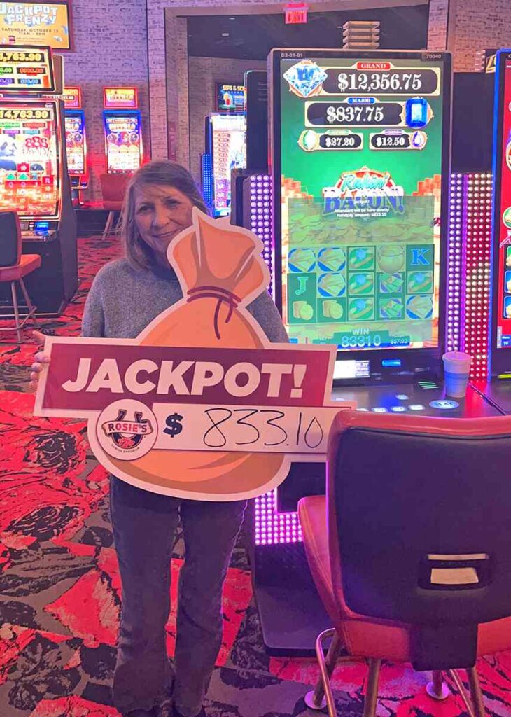 Recent jackpot winner Linda holding a sign that says JACKPOT!